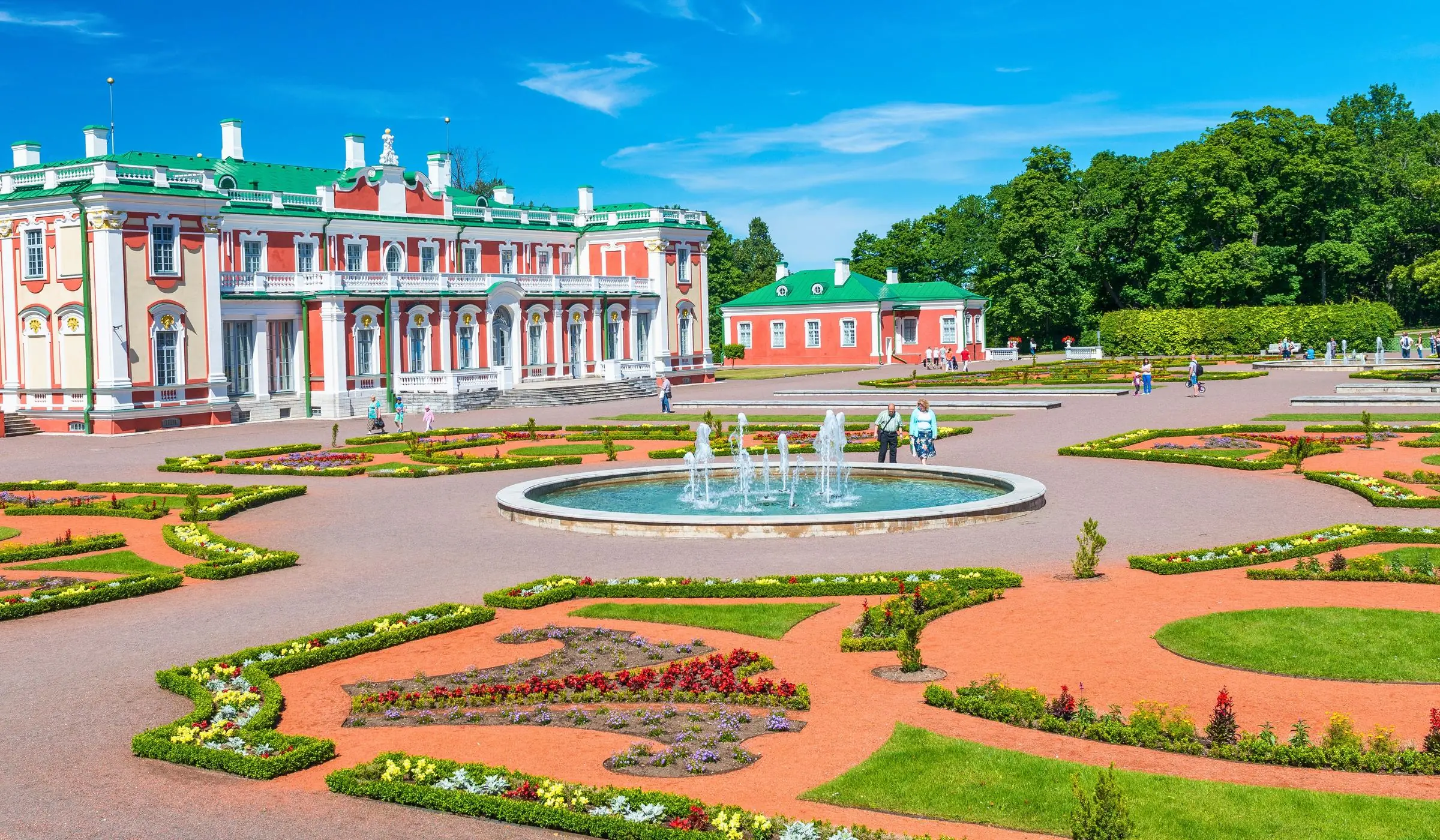The red and white Baroque facade of Kadriorg Palace surrounded by manicured gardens