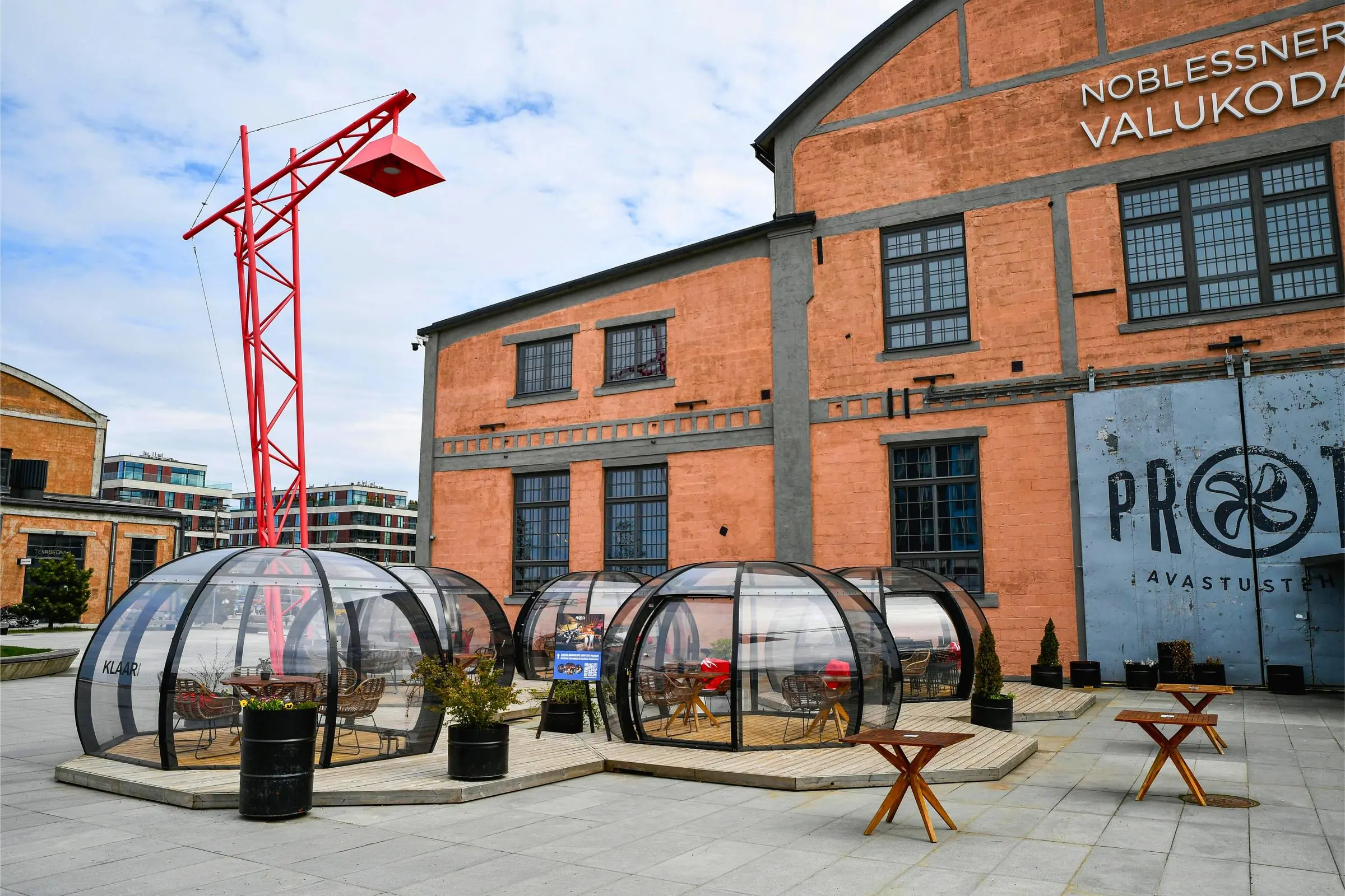 Exterior view of PROTO Invention Factory in Noblessner showing the historic red brick foundry facade and outdoor cafe terrace tables